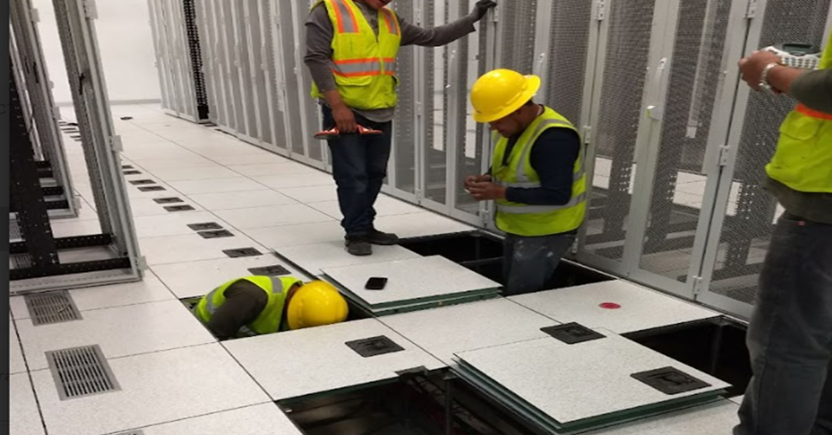 Técnicos instalando piso elevado en centro de datos, con racks de servidores y canalización inferior, proyecto Arcondec Querétaro